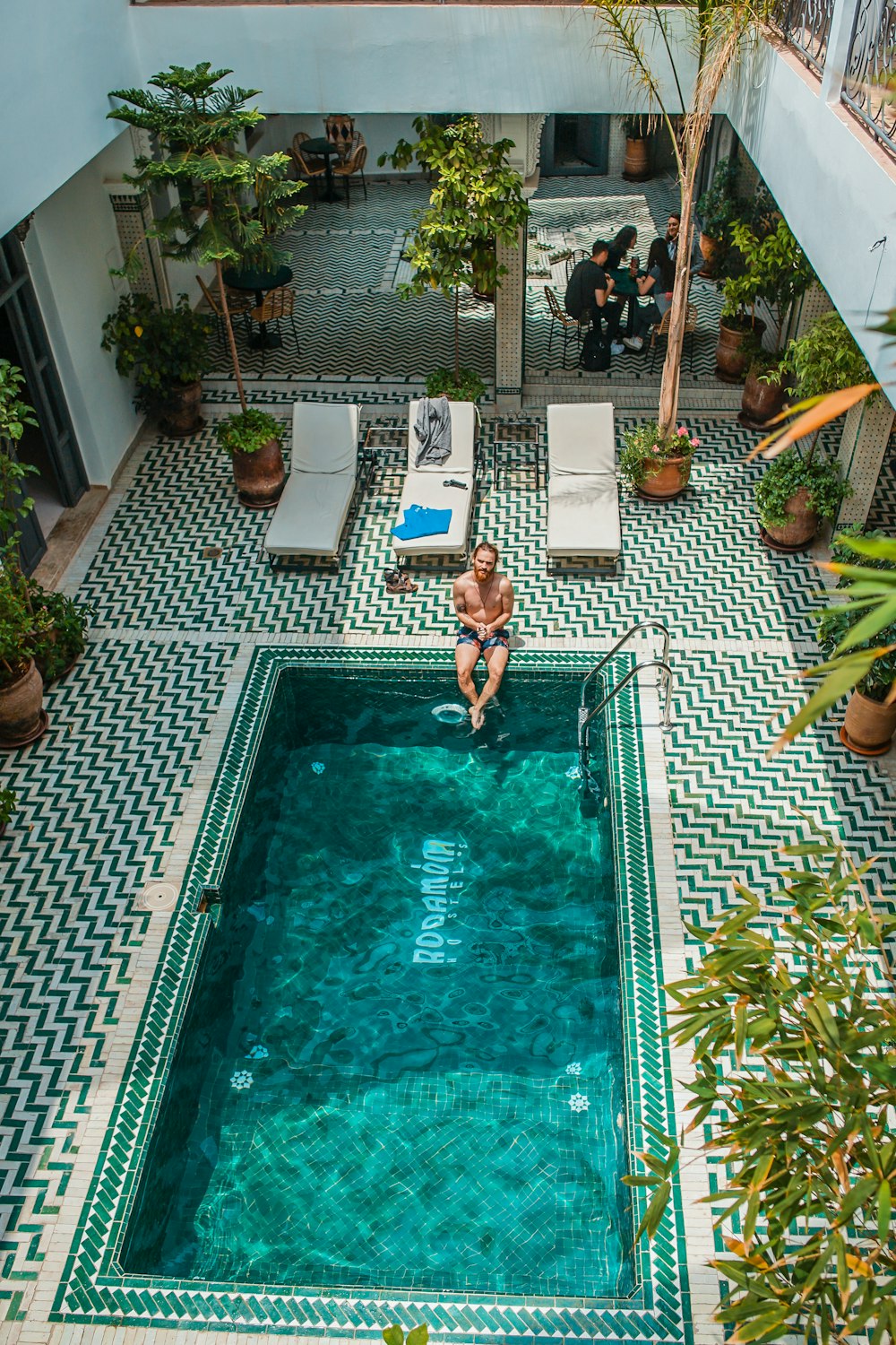 person sitting beside pool during daytime