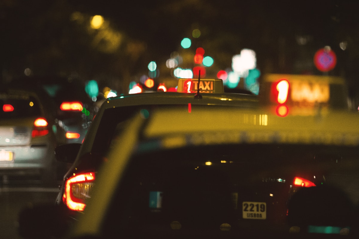 Two taxi cabs on a city street at night
