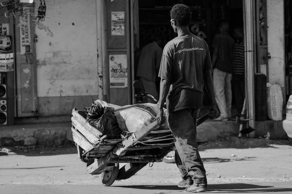 grey scale photo of man pushing cart