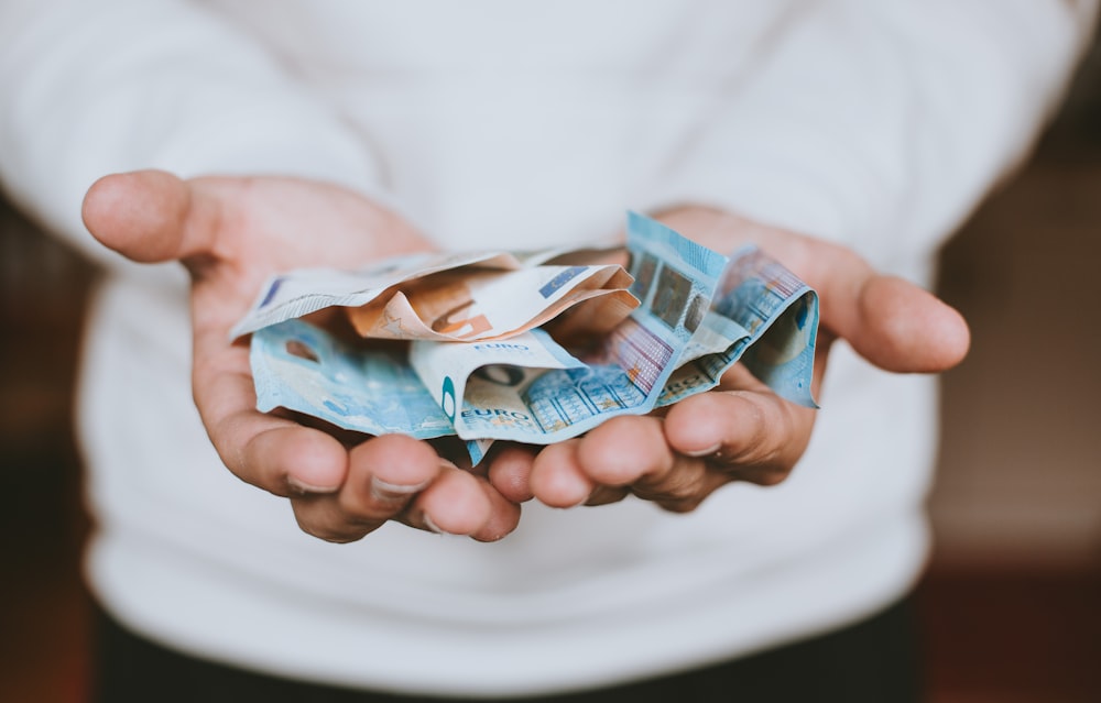 A person holding euro notes in both hands outstretched