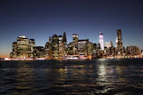 An elegant city skyline at dusk with shimmering lights reflecting on glass buildings.