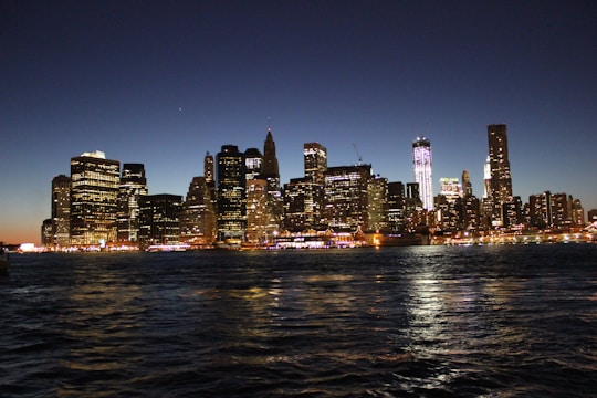 A sleek, modern city skyline at dusk with golden lights reflecting on glass buildings.