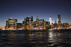 An elegant city skyline at dusk with shimmering lights reflecting on glass buildings.