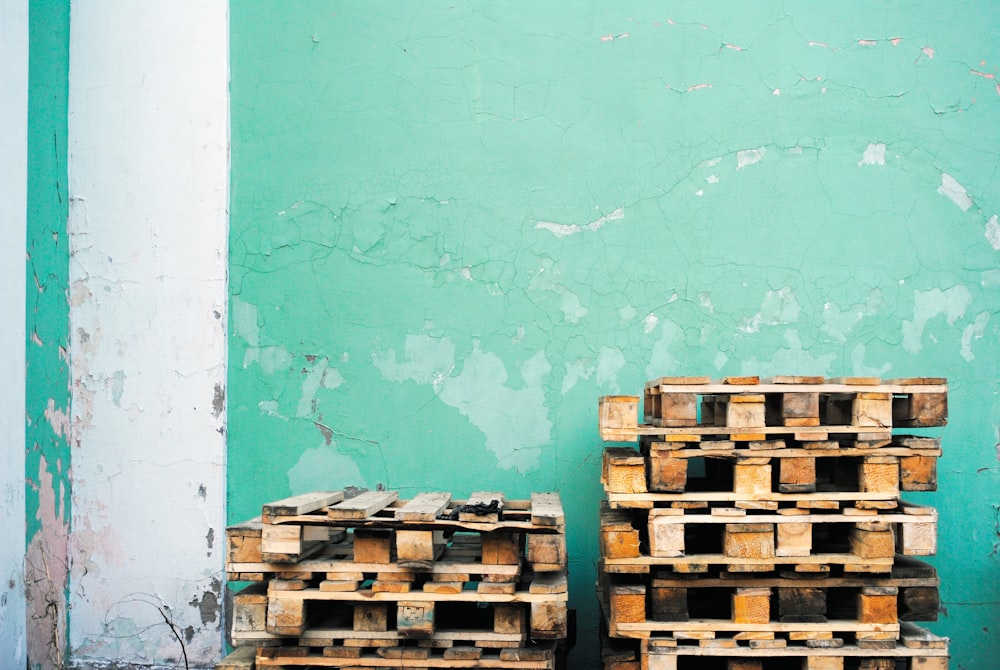 mucchio di lotto di pallet di legno marrone vicino a parete verde