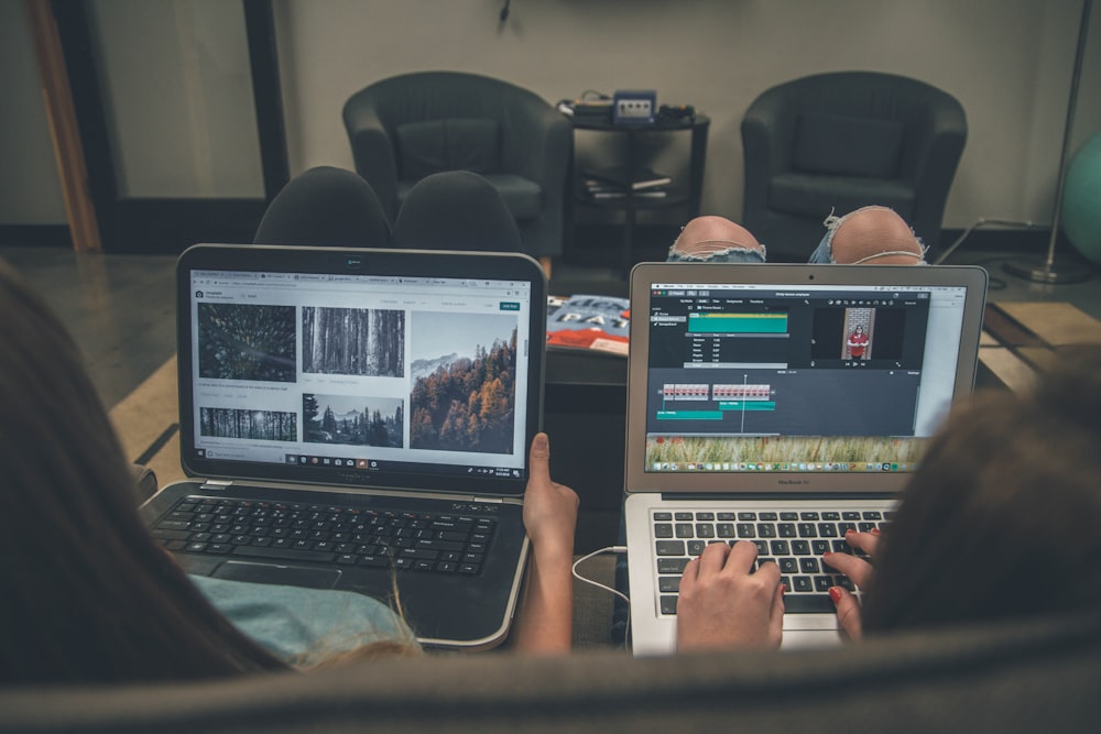 two person with laptop on lap sittig