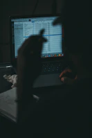 Close-up of hands organizing media files on a laptop with vibrant red and green color highlights.