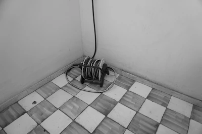 Flexible cleaning hose coiled neatly beside a floor cleaning machine on a factory floor.