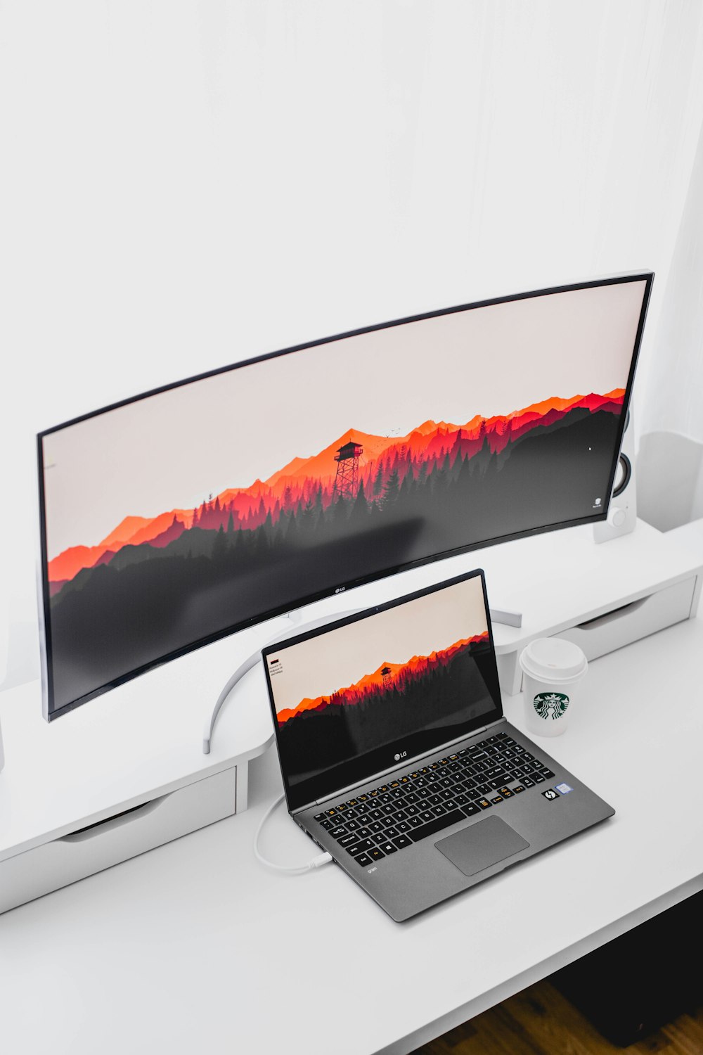 laptop computer beside curved monitor