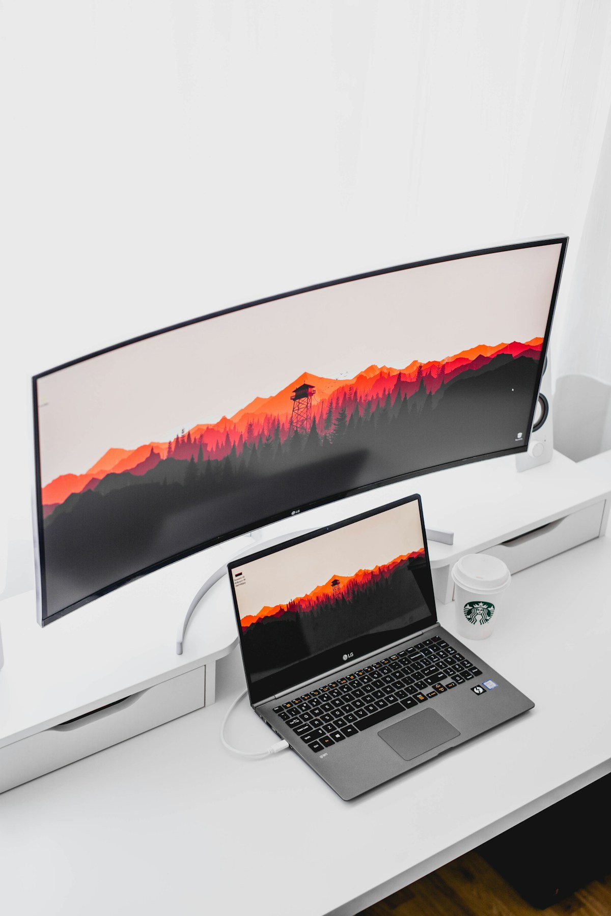 Laptop connected to a large curved external monitor on a white desk, showing a one-cable docking station setup