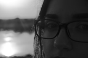 Side profile of a person trying on prescription glasses in front of a bright, airy window.