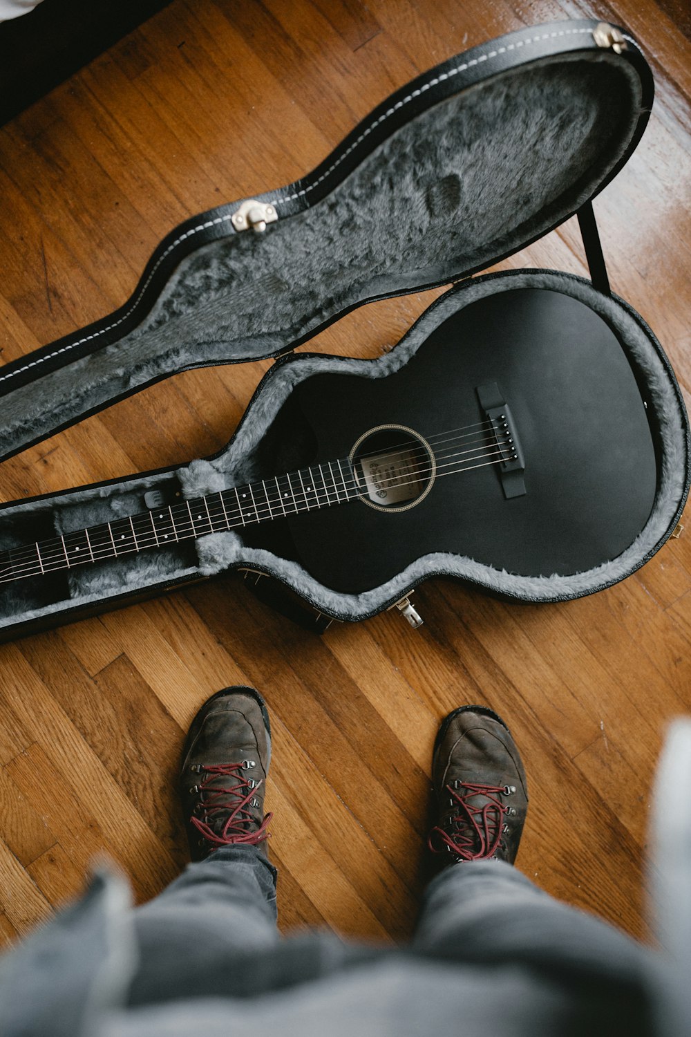 personne prenant une photo de guitare classique noire à l’intérieur de l’étui de guitare noir et gris