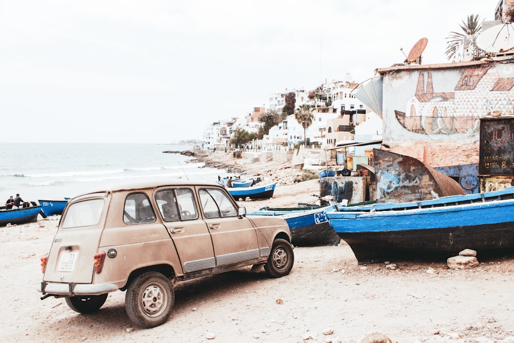 red station wagon near blue and black boat at daytime