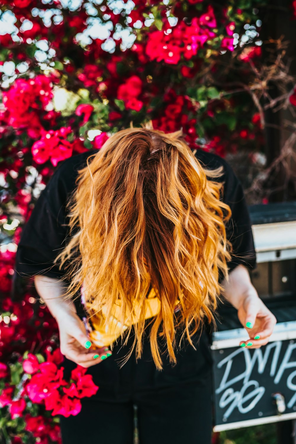 Frau, die mit rotem Bougainvillea-Pflanzenhintergrund nach unten schaut