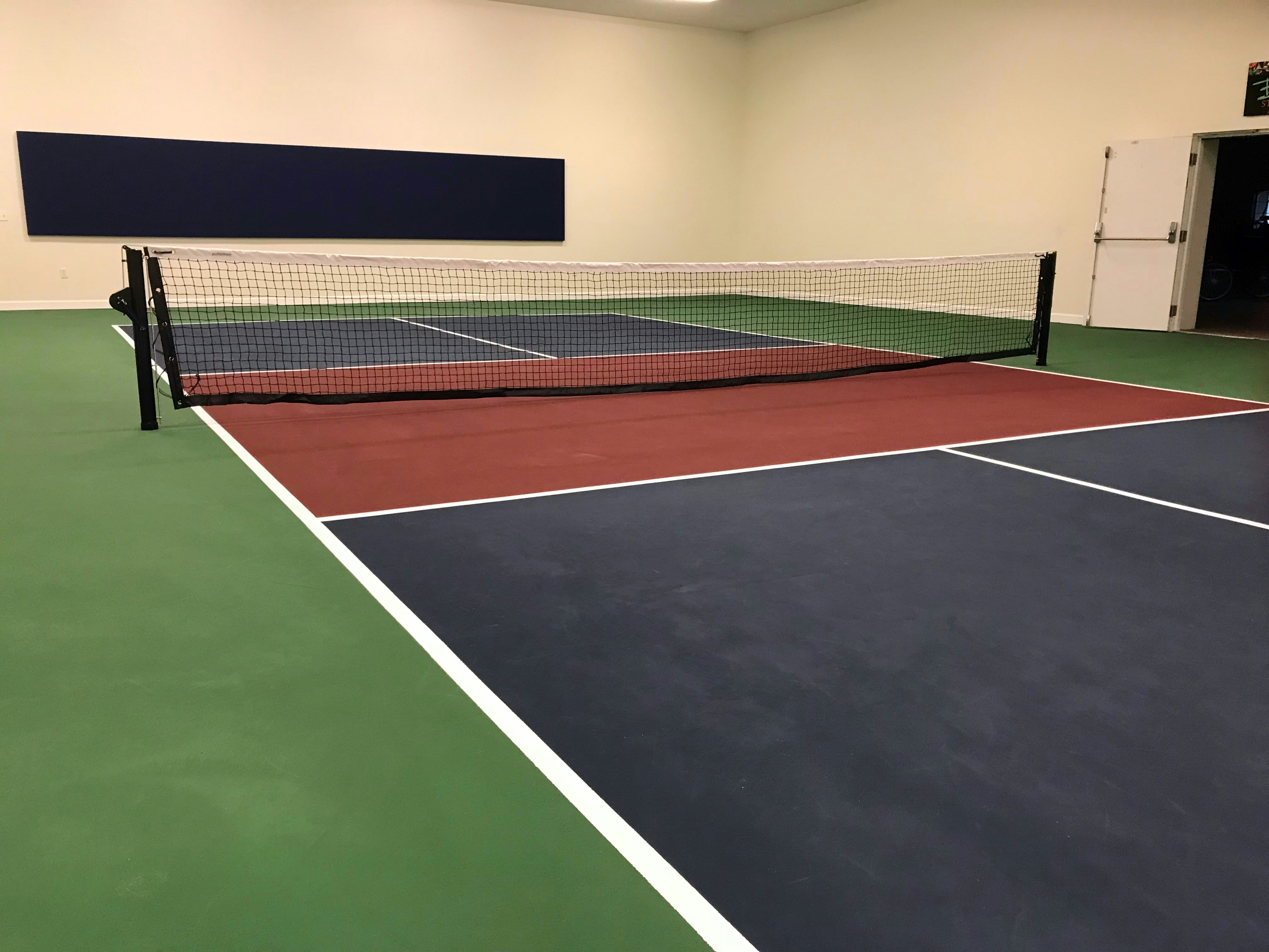 Premium indoor pickleball court interior with professional lighting and green acrylic surface