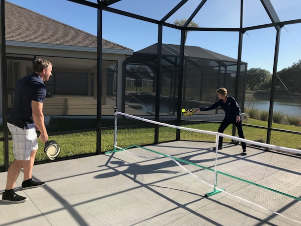 A school gymnasium with children playing pickleball using pickzone portable nets and paddles.