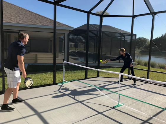 A lively group of players mid-match on colorful pickleball and tennis courts, laughing and cheering under bright skies.