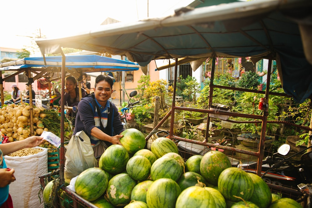 person standing in front of watermelon filled display rack