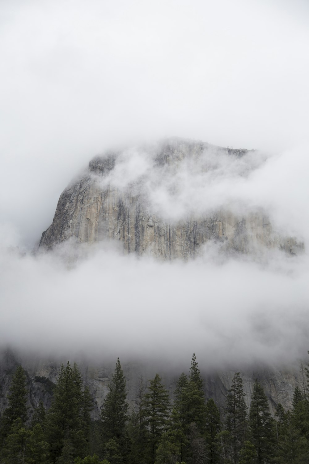 Montanha marrom cercada por nuvens