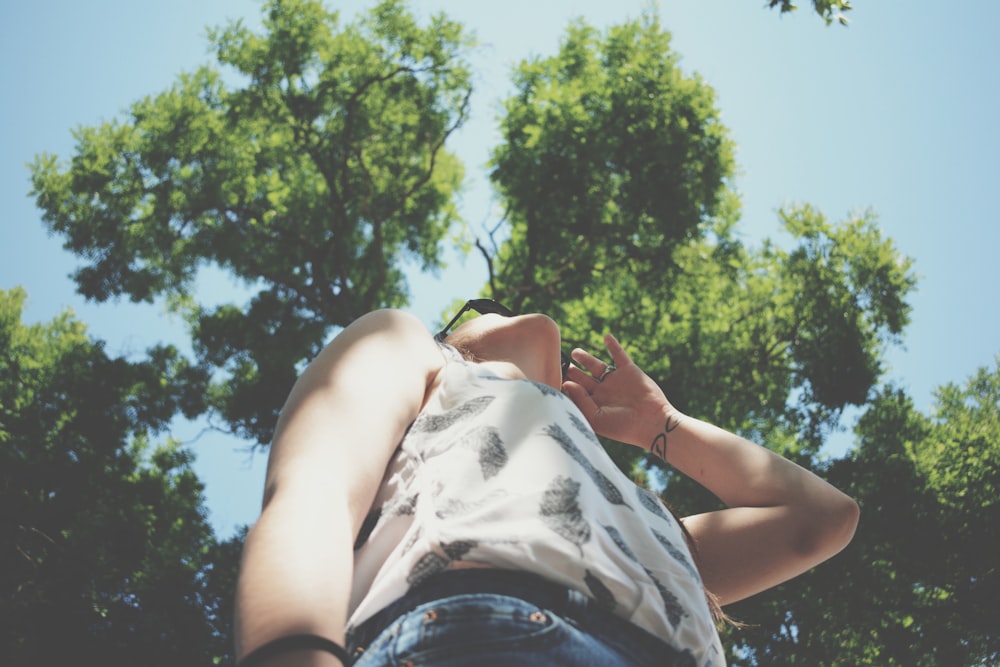 below angle photo of person standing beside tree