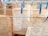 Several pages of old text with faded writing are clipped to clotheslines using blue and grey clothespins. The setup appears to be against a brick or textured wall, hinting at an informal preservation or drying process.