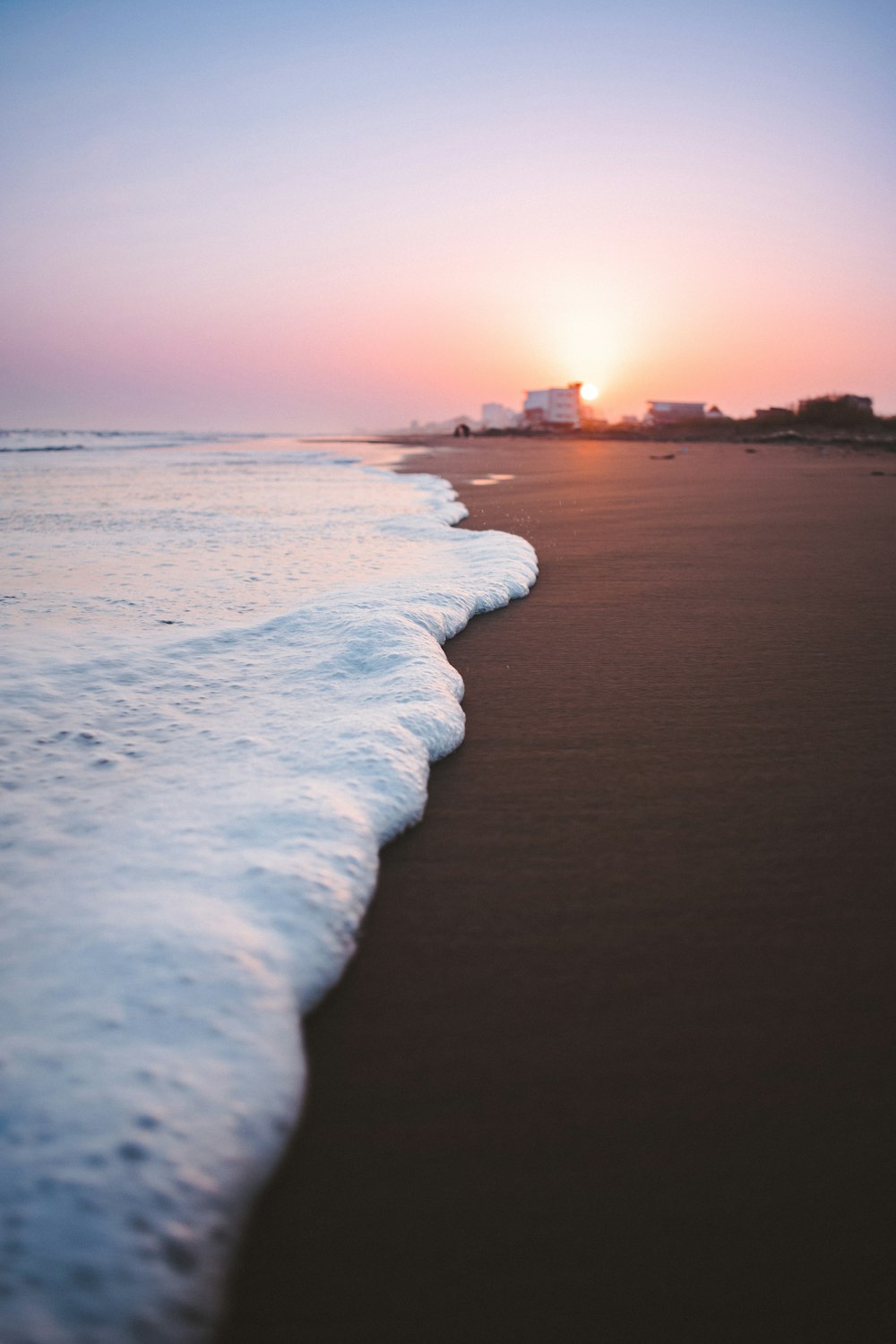 Ondas na areia marrom fotografia closeup durante o pôr do sol