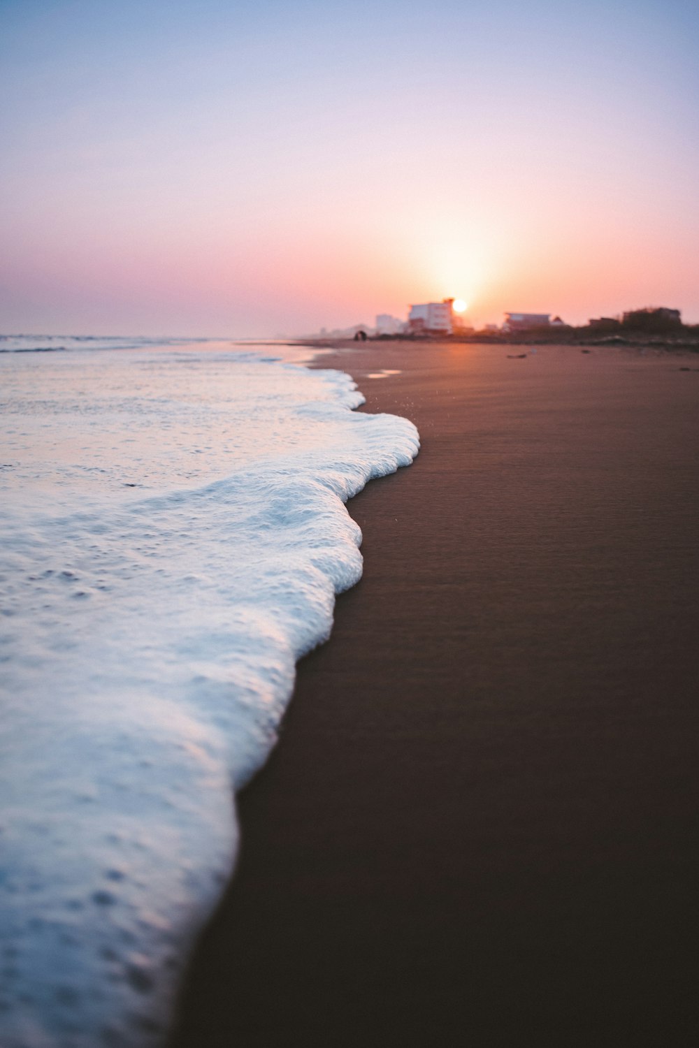 waves on brown sand closeup photography during sunset