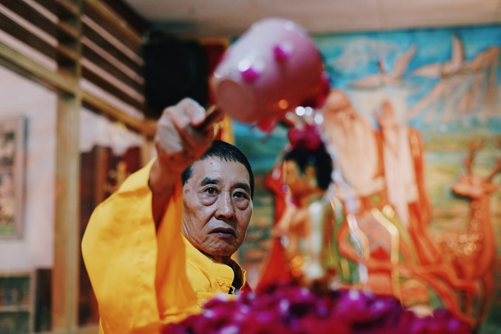 man pouring water on purple petaled flower inside well lighted room