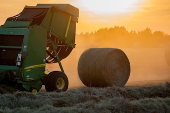 Modern agricultural machinery working in a green field at sunrise