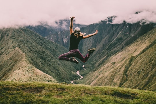 woman jumping on green mountains in Inca Trail Peru