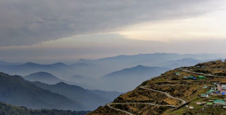 A scenic view of Kodaikanal hills shrouded in mist with a winding road inviting travelers.