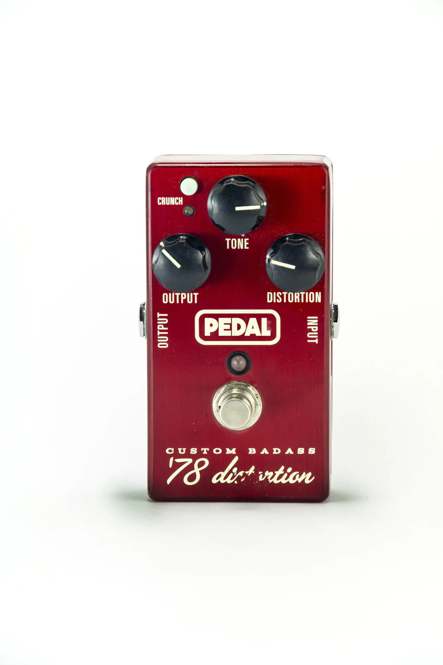 Pedal de distorção para guitarra nas cores vermelho, branco e preto sobre um pedalboard