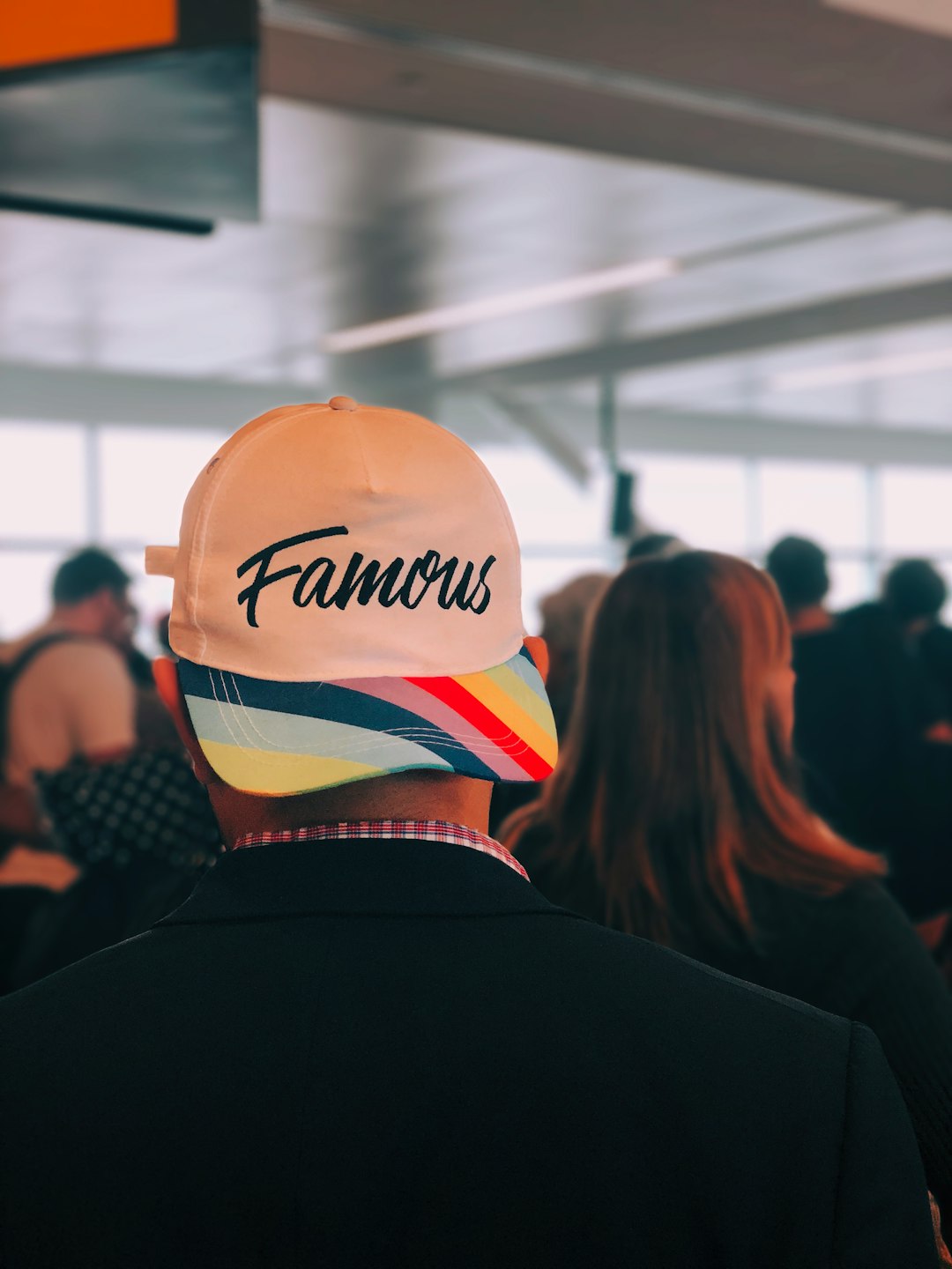 man wearing multicolored Famous cap