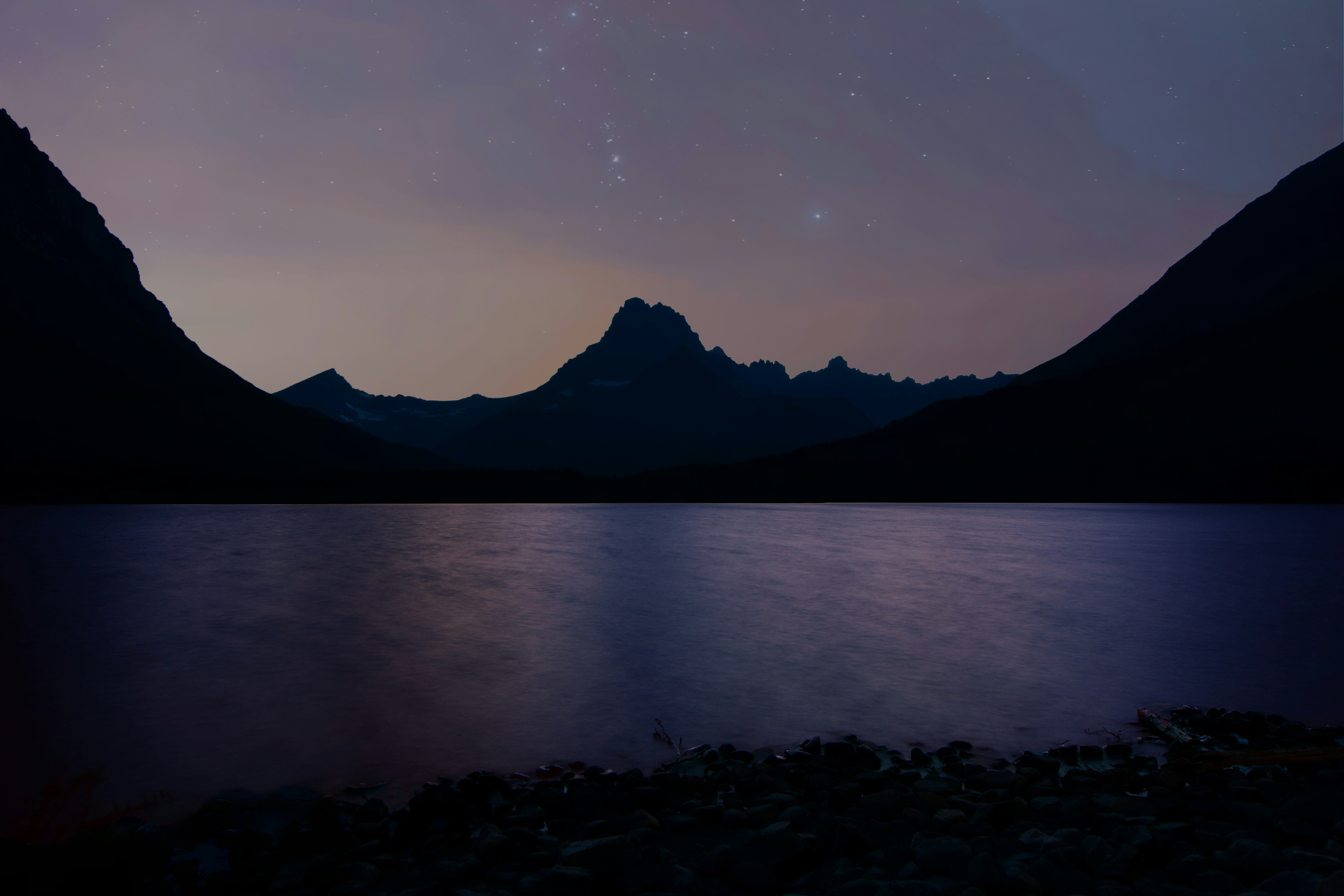 body of water near mountain glacier national park teams background
