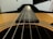 A close-up of a nylon-string guitar resting on a wooden table.