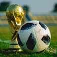 soccer ball beside trophy on soccer field