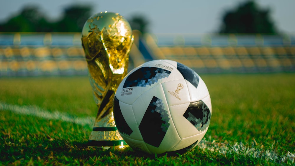 bola de futebol ao lado do troféu no campo de futebol