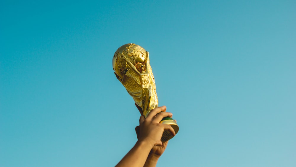 Persona que sostiene el trofeo de oro