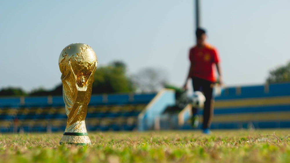 Fotografia de foco seletivo de troféu dourado no campo de grama durante o dia