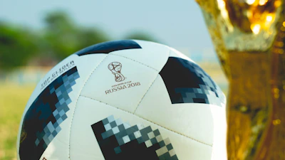 Close-up of a hand holding a soccer ball with a golden ticket for the 2026 World Cup.