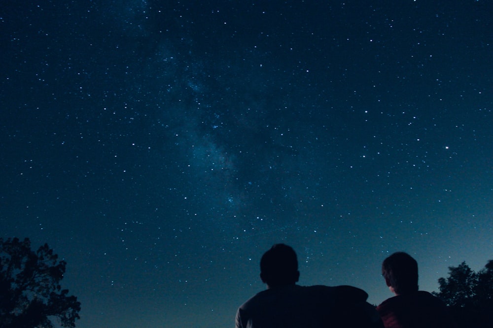 photo de silhouette de deux personnes regardant des étoiles
