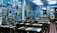 The interior of a cozy restaurant is decorated with numerous framed photographs and posters on the walls, creating a nostalgic atmosphere. Wooden tables and chairs are arranged neatly throughout the room, with patrons sitting and enjoying their meals. The lighting is soft, complementing the vibrant blue walls.