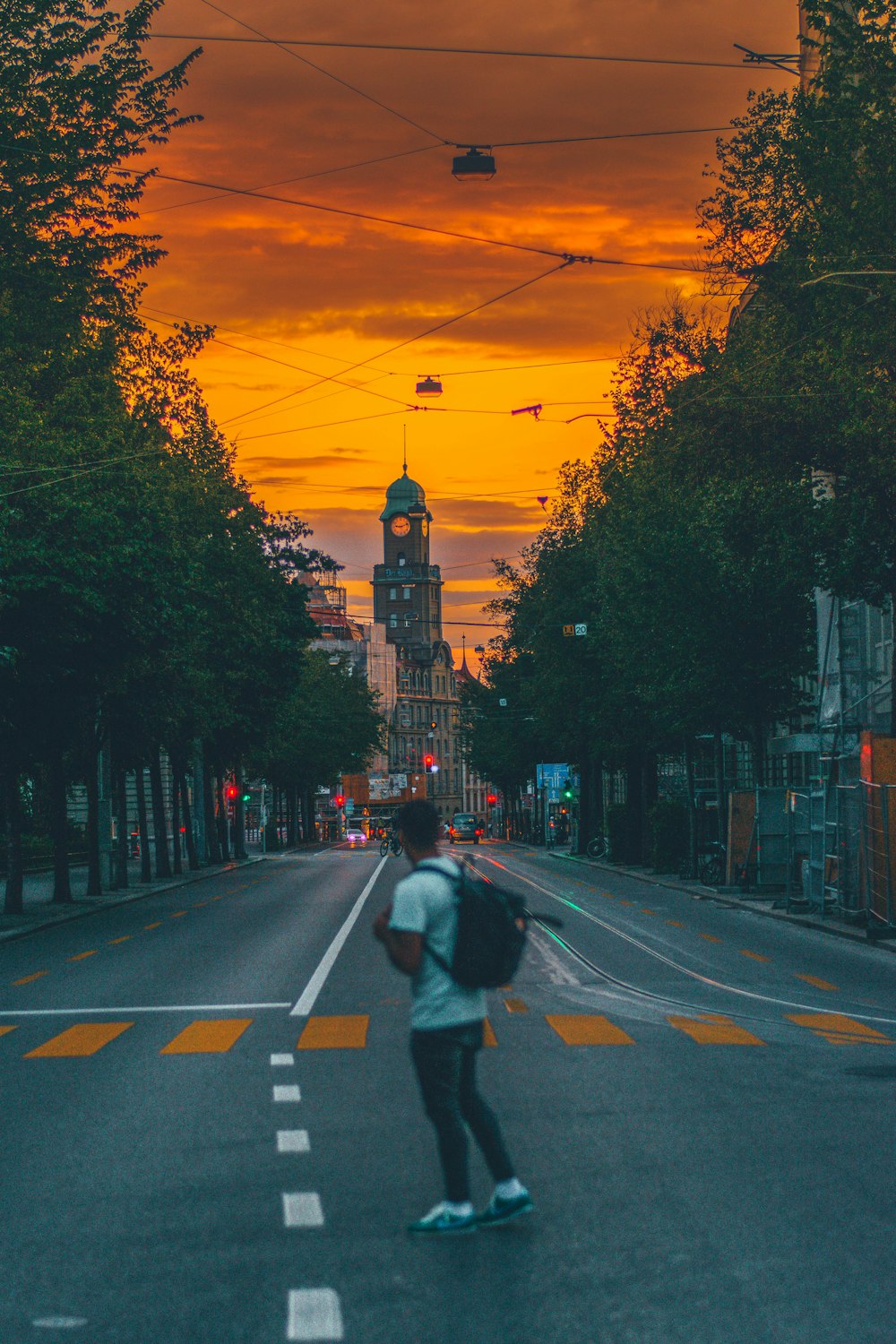 man standing on road near trees during sunset