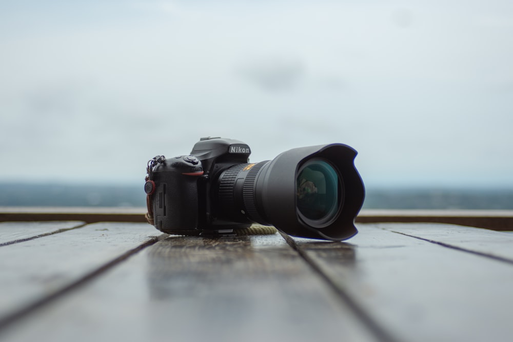 câmera DSLR Nikon preta no piso de prancha de madeira fotografia de foco raso