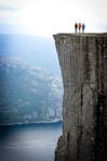 three people standing on cliff