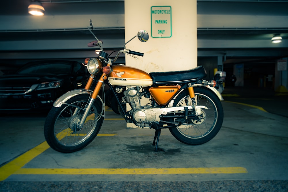 person taking photo of orange Honda standard motorcycle