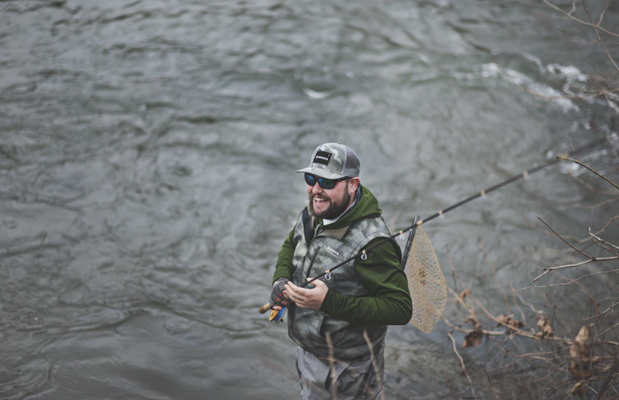 Smiling guide holding a fly rod by the water