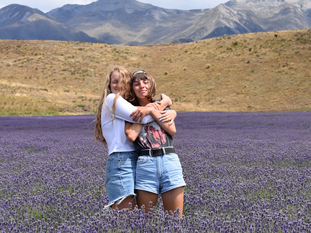 woman hugging another woman on purple flower field