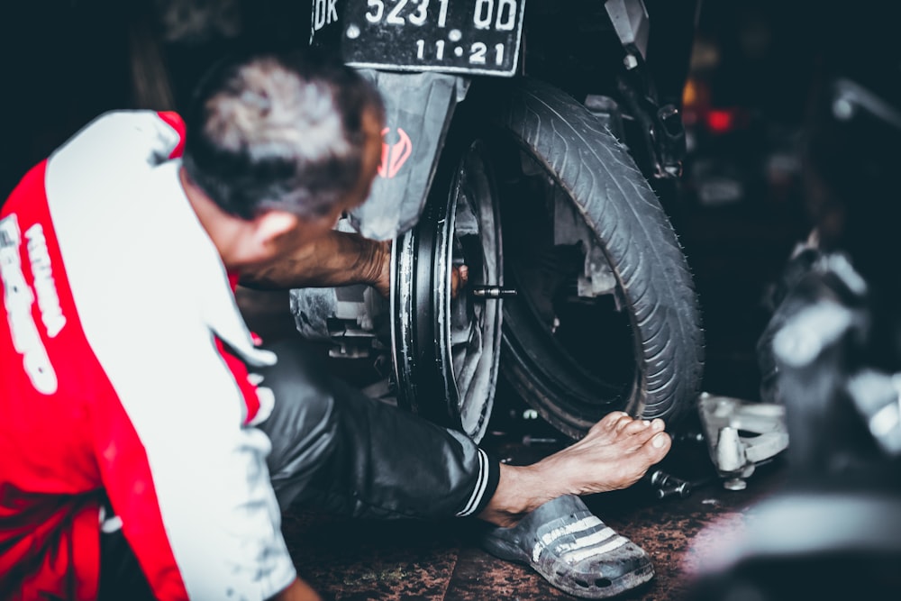 homme changeant le pneu de moto