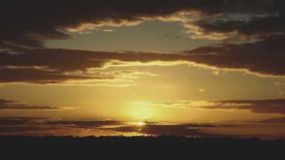 A golden-hued sunset with zodiac symbols subtly appearing in the sky.