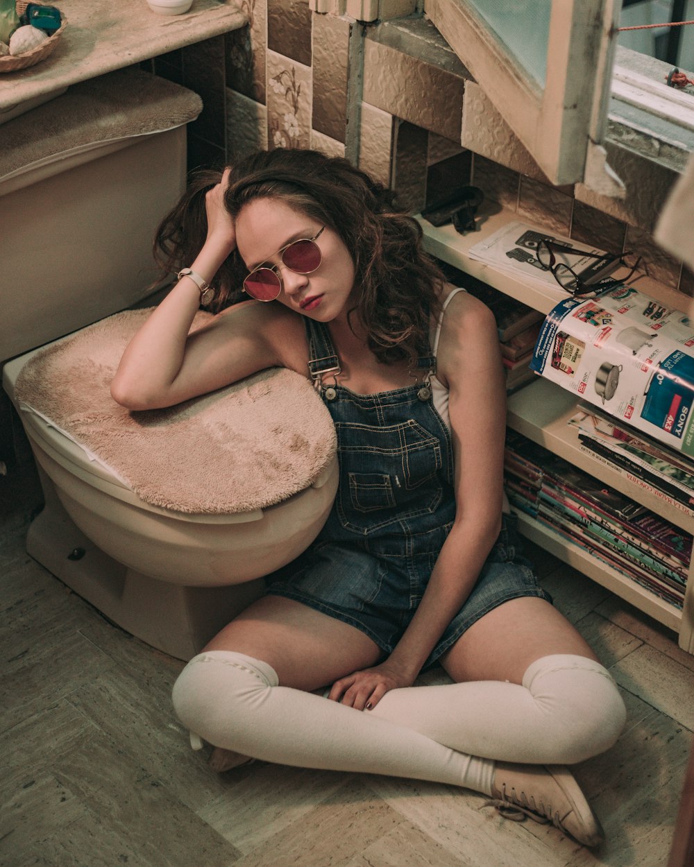 woman wearing blue denim jumpsuit beside white toilet bowl